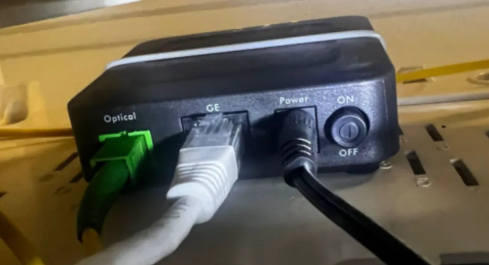 The ports on an Adtran 611: the green fibre plug in Optical, an Ethernet cable in GE, and the power cable
